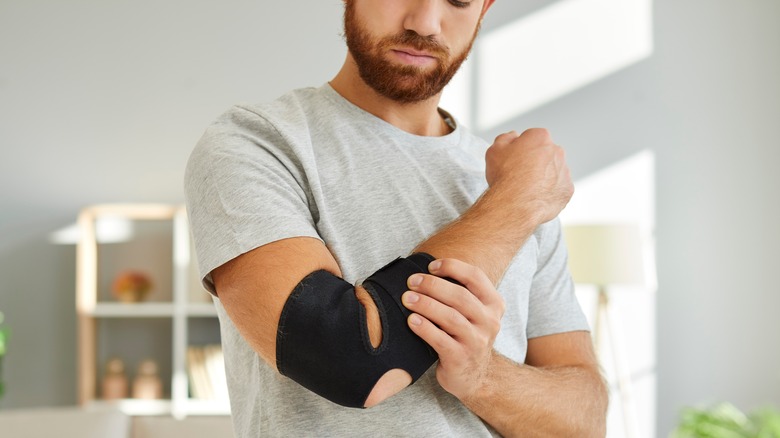 A man examines his elbow brace