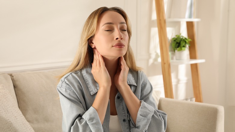 woman touching thyroid gland