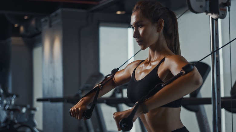 woman toning up her arms on a cable machine