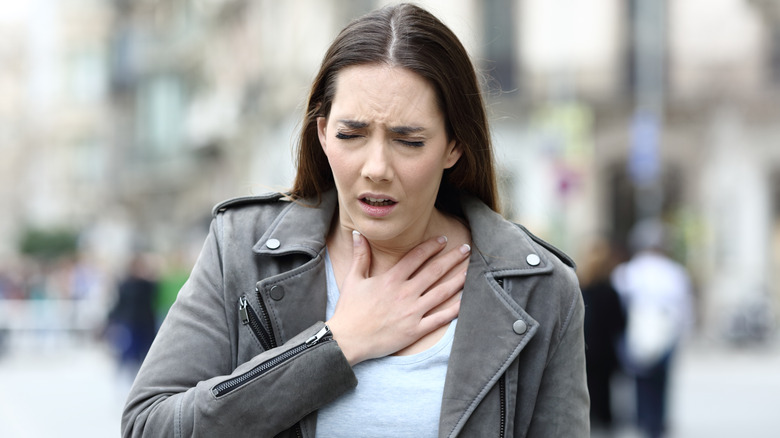 woman wheezing while walking on city street