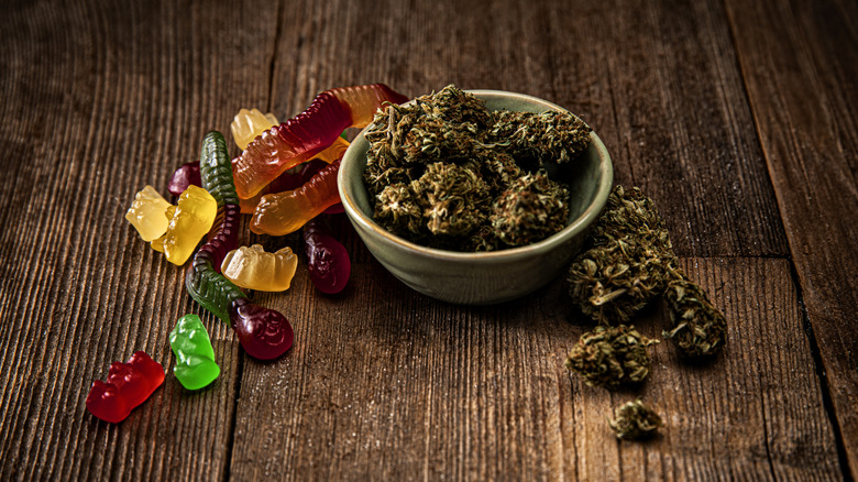 A small bowl of cannabis next to colored gummies