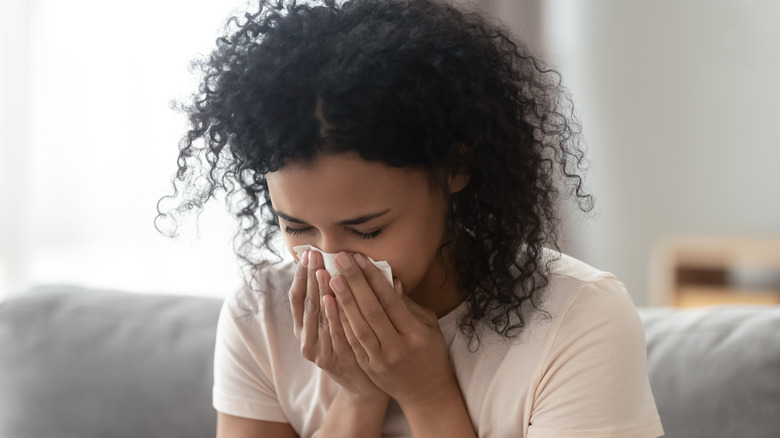 Young woman blowing nose