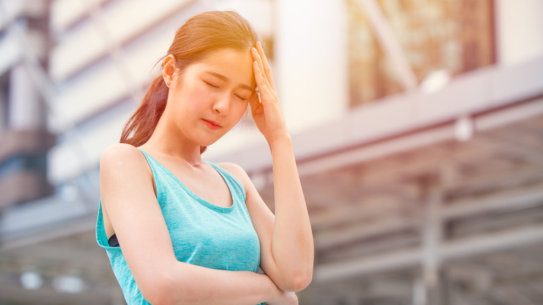 woman with hand on head in sun