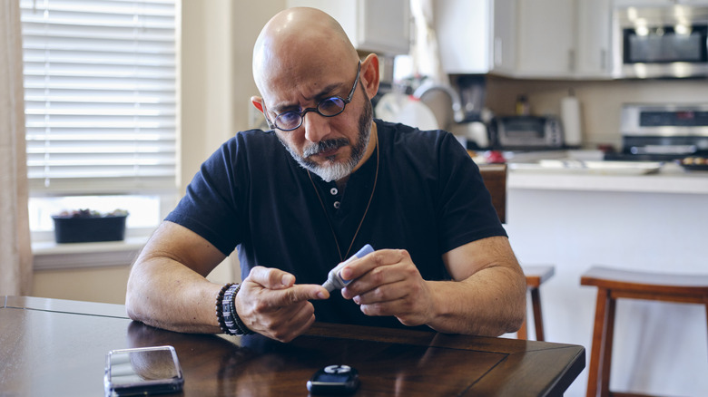 A man pricking his finger to test his blood