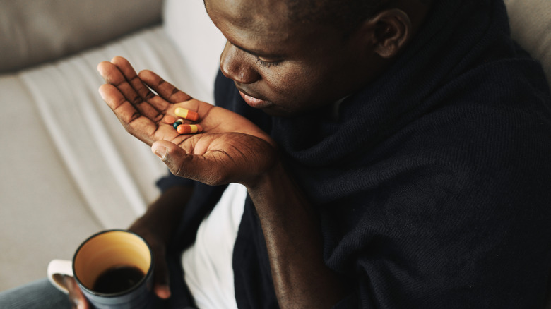 man taking diabetes medication with coffee