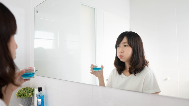 A woman uses mouthwash