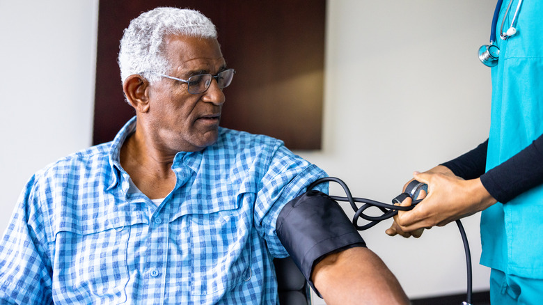 Older man glasses sat blood pressure cuff nurse