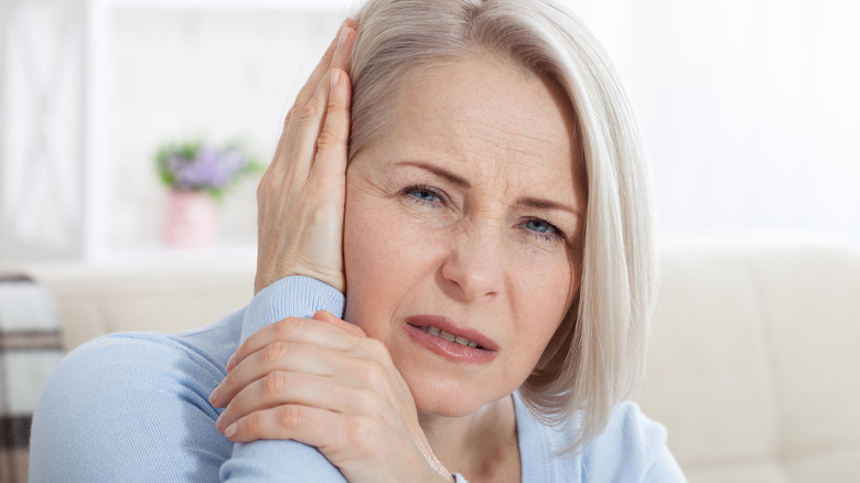 Older woman holding ear in pain