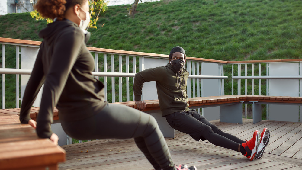 couple doing exercises outside in masks
