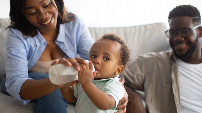 Smiling family feeding baby bottle