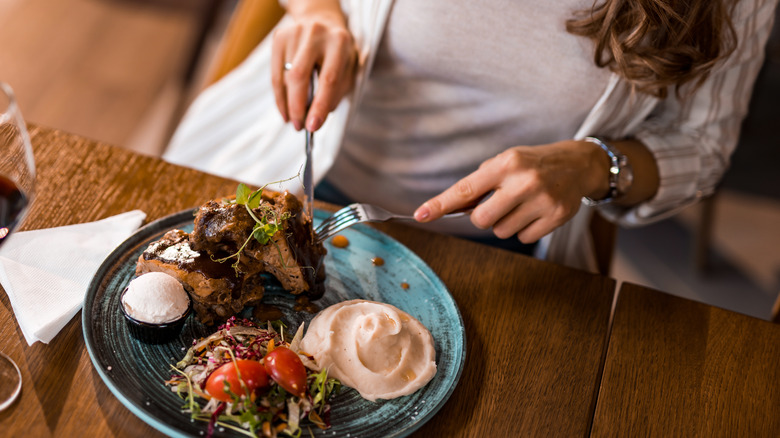 woman's hands cutting steak 