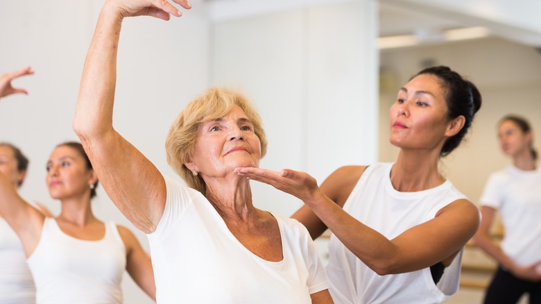 older woman in barre class with instructor