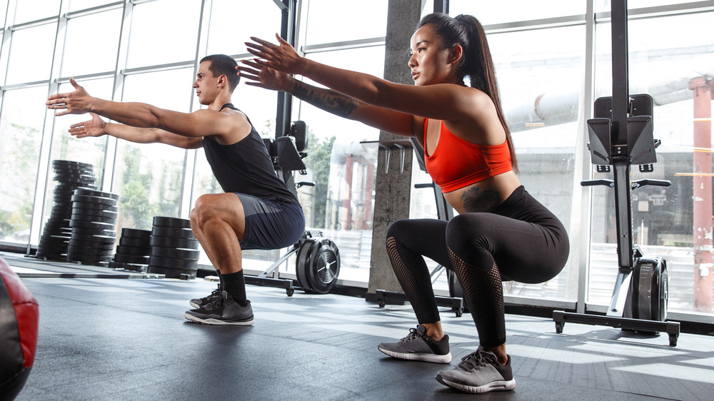 man woman performing squats