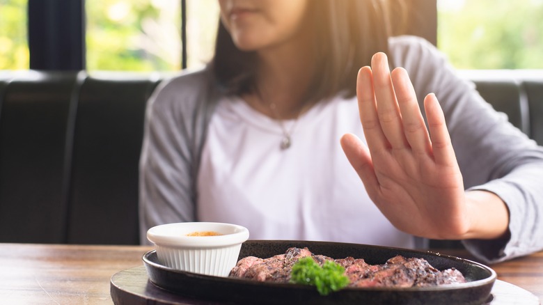 Woman pushing away plate of meat