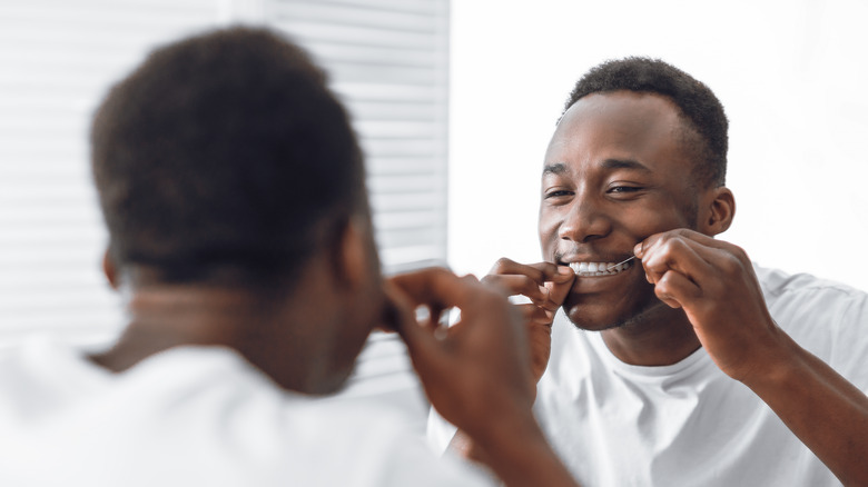 man flossing teeth