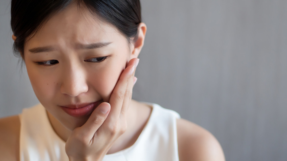 Woman holding the side of her mouth with tooth pain