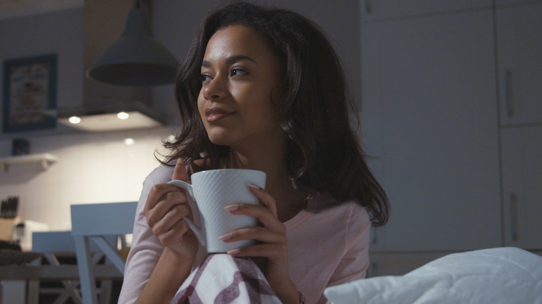 woman drinking tea in dark bedroom