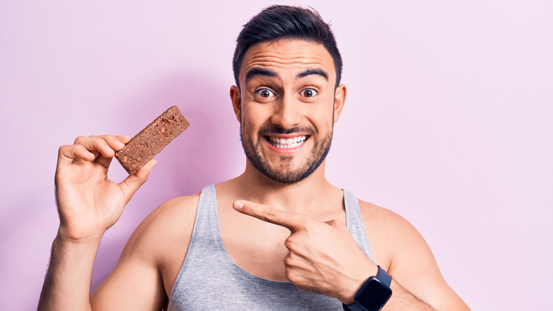 a man points to a protein bar he's holding
