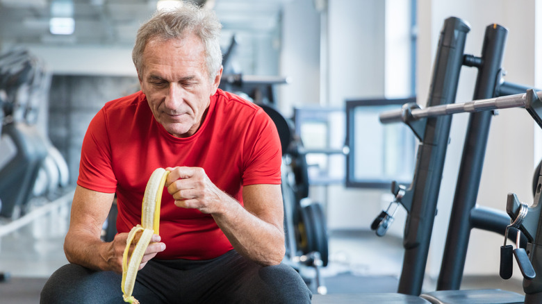 older man peeling a banana at the gym