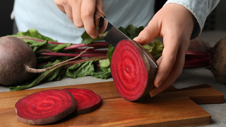 woman slicing beets on chopping board