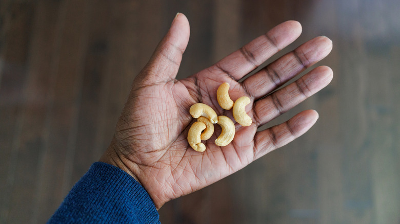 A woman's hand holding six cashews
