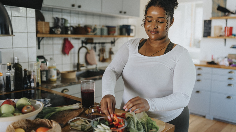 A woman arranging vegetables in a plastic container