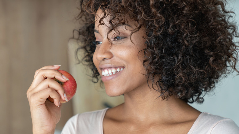 Smiling woman eating apple