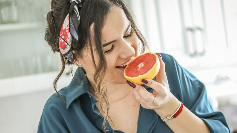 A woman enjoying a slice of grapefruit in her kitchen