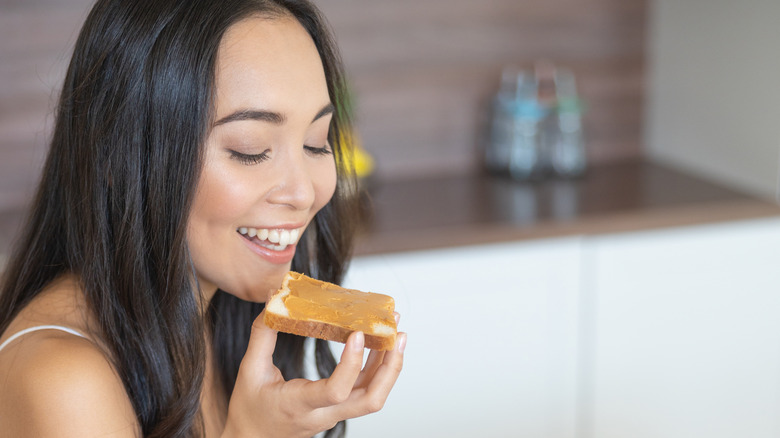 woman eating peanut butter on white bread