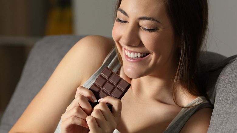Young woman eating a chocolate bar and smiling