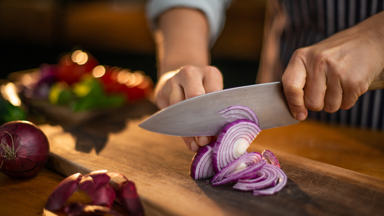 Person slicing red onions