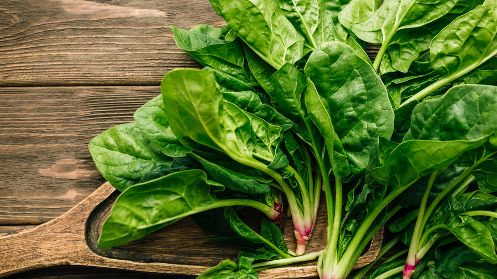 bushels of spinach on a wooden bench 