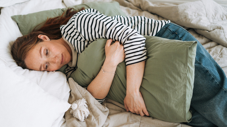 Sad woman lying down on bed