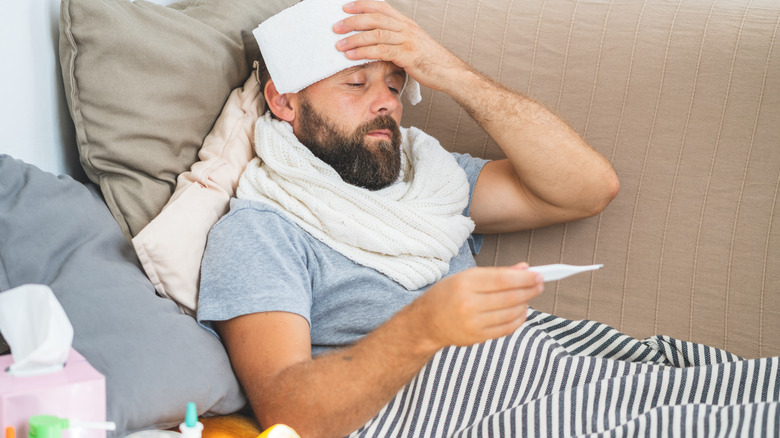 sick man taking temperature