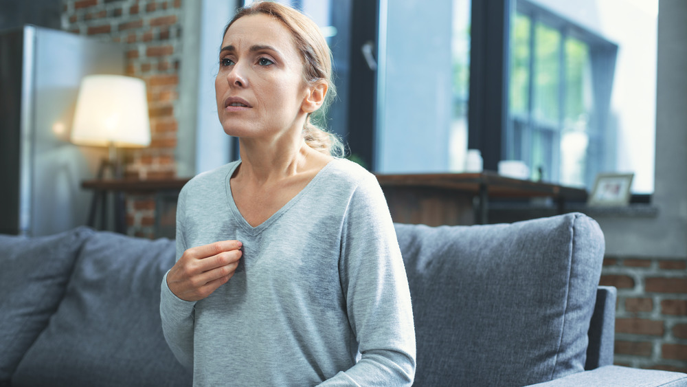 Middle-aged women sitting on couch experiencing hot flash