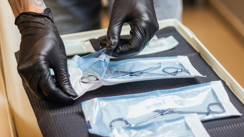 gloved hands prepare a piercing setup