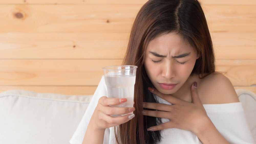 Woman with cup of water, has hiccups