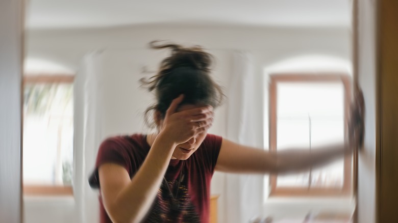 woman in distress holding her head and leaning on wall