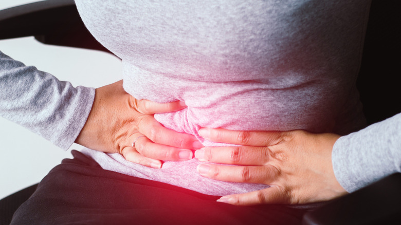 woman squeezing stomach in pain