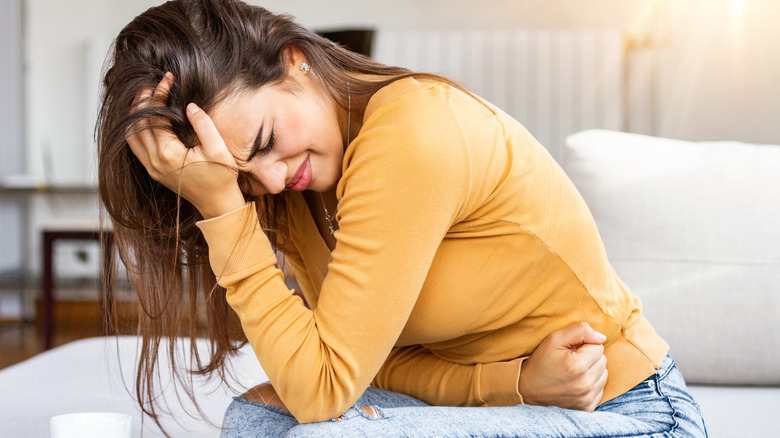 woman holding her head and stomach