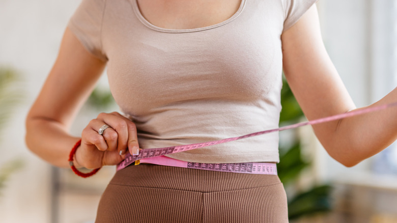 woman holding tape measure around her waist