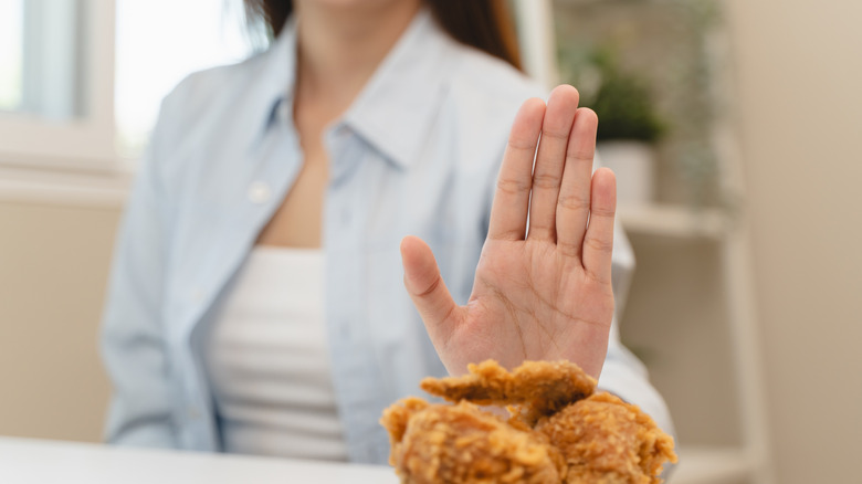 woman pushing away plate of chicken
