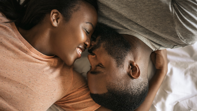 smiling couple lying in bed 