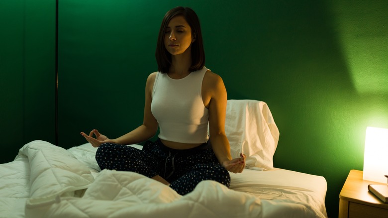 Woman sitting cross legged meditating in bed