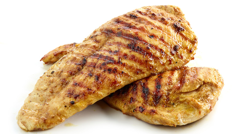 Two pieces of grilled chicken on a white background