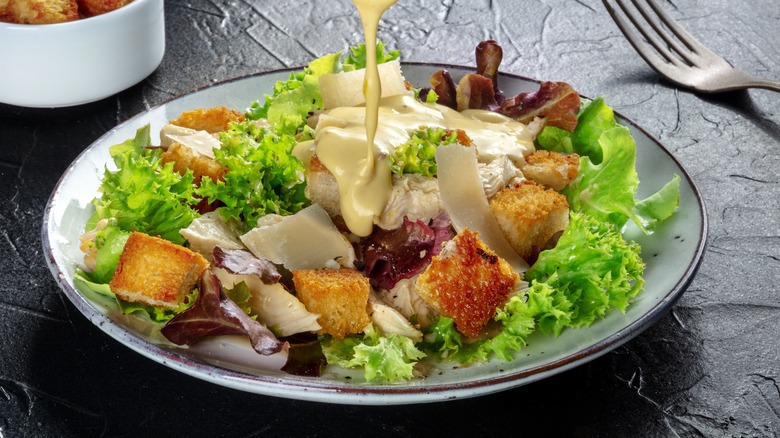 Dressing being poured over a salad