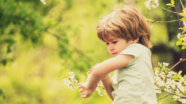 young boy picking at a scab on his arm 