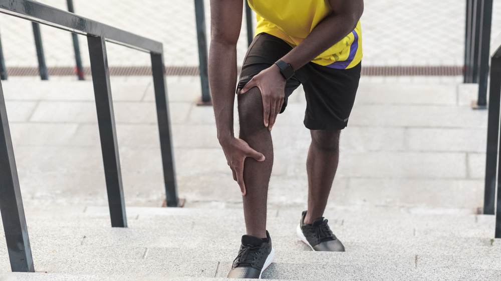 Man on stair holding his shin and knee