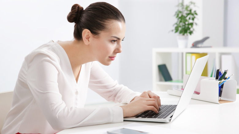 woman slouching over laptop