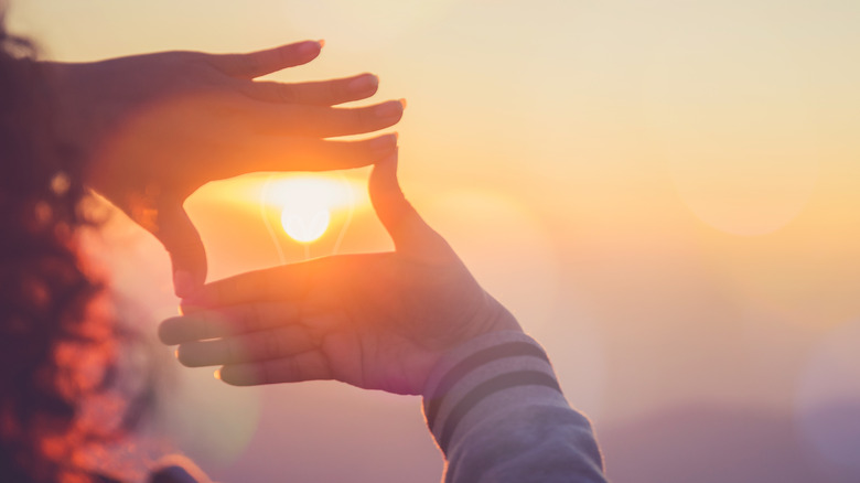 Female outside framing the sun with her hands